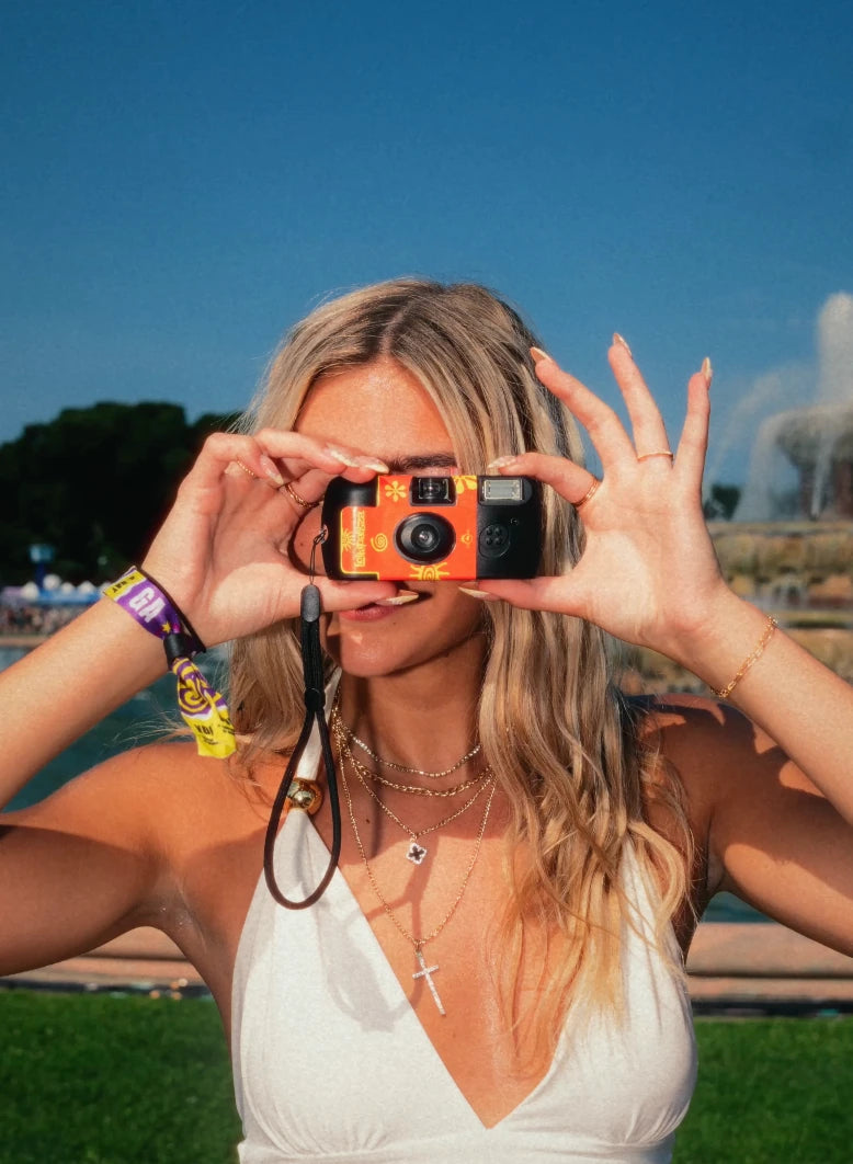 Strap x Lollapalooza: A festival guest holding her custom red and yellow camera